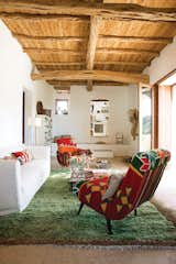 Living Room, Rug Floor, Chair, Sofa, Coffee Tables, Floor Lighting, Lamps, and Storage Rug designer Nani Marquina and photographer Albert Font created their home in a peaceful corner of the Spanish island of Ibiza. In their living room is a pair of kilim-covered chairs by Philippe Xerri, a chest of drawers by Piet Hein Eek, and a handmade Tunisian rug that provides bursts of color amidst the overall color scheme of white, ecru, and cream.  elliekdesign.com’s Saves from 12 Mediterranean Homes That Are the Antidote to Mid-Winter Blues