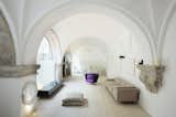 Living Room, Sofa, and Media Cabinet Vaulted cloisters in Barcelona that date back to the 1600s were converted into a vaulted residence with hand-carved stone features columns and arched stained glass windows.  Photo 2 of 11 in Discover 10 Impressive Spaces With Arched Windows and Doors