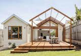 This timber-clad Edwardian home in the beachside suburb of Sandringham in Melbourne, Australia, features a custom rear extension One of the gable roofs extends out to the deck as a timber pergola above an open-air dining area. Glazed sliding doors connect the interiors with the elevated patio.