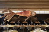 Dining Room, Chair, and Table IZAKAYA, the hotel’s restaurant and bar, is a sophisticated and serene space where a giant fish mobile made of beech wood hovers over a large communal table as chefs prepare exquisite Japanese cuisine.  Photo 10 of 15 in This Munich Hotel Looks Like It's From a James Bond Movie