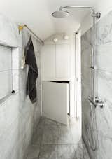Bath Room, Marble Floor, Wall Lighting, Marble Wall, and Full Shower When architects Silvia Ullmayer and Allan Sylvester worked with joiner Roger Hynam to reinvent an apartment for metalworker Simone ten Hompel, they created a covered space in the bathroom to conceal the front loader washing machine.  Photo 5 of 8 in 8 Bathroom Storage Hacks You Probably Haven’t Tried Yet