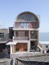 Exterior, Concrete Siding Material, House Building Type, and Curved RoofLine To further reduce the possibility of water seepage, a vaulted structure was used for the third floor extension, so rainwater flows down from the roof and drains away.  Photos from A Vaulted Concrete Addition Protects This Sea Captain's Home