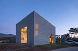 A cube-shaped home in South Korea with the form of a small, gabled house cut out to create a wide passageway