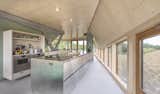 Kitchen, Wood, Ceiling, Metal, Wall Oven, Drop In, Wood, Wood, Open, and Cooktops The open plan kitchen on the ground floor.  Kitchen Wall Oven Ceiling Open Photos from A Tent-Shaped Home in the Netherlands Crouches Between Natural Dunes