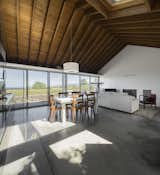 Dining Room, Chair, Pendant Lighting, Concrete Floor, and Table The western windows of the living room look out to coast.  Photo 8 of 14 in A Bright Red Island Residence Embraces a Linden Tree