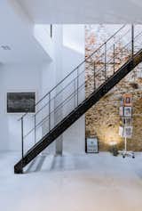 Exposed brick walls work with a black steel staircase and polished concrete floors to give the interiors an edgy and modern atmosphere.