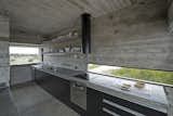 A streamlined kitchen houses a concrete slab countertop.