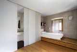 Bedroom, Wall Lighting, Storage, Medium Hardwood Floor, Shelves, and Bed A warm and simple bedroom with an ensuite bathroom.  Photo 6 of 15 in A Spanish Architect Transforms a Medieval Townhouse Into a Stunning Rental