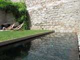 Outdoor, Grass, Small Pools, Tubs, Shower, Plunge Pools, Tubs, Shower, Stone Fences, Wall, Small Patio, Porch, Deck, and Back Yard An old cistern found on the original site is now a black concrete plunge pool.  Photo 14 of 15 in A Spanish Architect Transforms a Medieval Townhouse Into a Stunning Rental