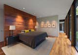 In the master bedroom, a wooden accent wall with coat hooks on one side serves as a partition for the bed. 