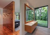 The bathroom has a large window that frames tree views.