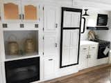 Kitchen, Medium Hardwood Floor, Cooktops, Subway Tile Backsplashe, Microwave, Wall Oven, and White Cabinet The kitchen has a fireplace, oven, microwave, electric cooktop and plenty of discreet storage.  Photo 10 of 16 in Hit the Road With This Chic Camper on Sale For $28K