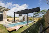 Outdoor, Grass, Wood, Back Yard, Small, Vertical, Shrubs, Lap, Small, Plunge, and Concrete A pergola keeps swimmers cool on hot days.  Outdoor Concrete Plunge Small Grass Back Yard Photos from A Concrete Abode Becomes a Surfer's Paradise