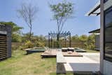 Outdoor, Grass, Wood, Back Yard, Shrubs, Small, Trees, Small, Plunge, Concrete, Vertical, and Lap A pool and sun deck on the eastern side of the plot.  Outdoor Shrubs Plunge Trees Lap Photos from A Concrete Abode Becomes a Surfer's Paradise