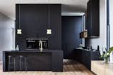 The sleek black kitchen is fitted with oak timber floors and brass accents to infuse additional sophistication into the space.

