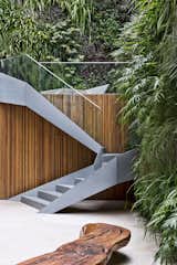 Staircase, Metal Tread, and Glass Railing Stairs lead up from the garden to the pool and deck.

  Photos from A Mesmerizing Pool Dominates This Brazilian Home