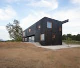 The house's dark façade, clad in vertically oriented, stained softwood timber slats, resembles the black volcanic stone structures that are commonly seen in the region.