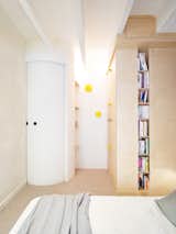 Bedroom, Bed, Bookcase, Accent Lighting, and Carpet Floor A curved sliding door serves as the entrance to the master bedroom.  Photos from This Compact Home in Paris Has Nearly 70 Concealed Closets