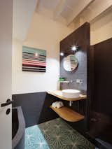 The simple bathroom was fitted with colored glass and black tiles. This space accommodates a generous bathtub and shower.