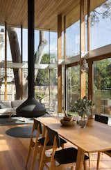 Dining Room, Chair, Table, Pendant Lighting, Hanging Fireplace, Medium Hardwood Floor, and Rug Floor Timber posts, which support a timber lined canopy overhead, were used as the boundaries of the pavilion structure.  Photos from An Airy New Pavilion Lets One Family Practically Live in a Park