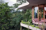 Robust, raw materials such as concrete, brick, and timber highlight the house’s sculptural form, while the glass walls create a sense of full immersion in the rainforest.