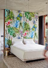 The wall in the master bedroom is upholstered in tropical print fabric by Christian Lacroix. 