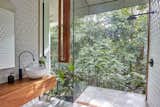 Bath Room, Wood Counter, Open Shower, Vessel Sink, and Concrete Floor An open, glass-encased shower gives the homeowners the sensation of bathing outdoors.  Photos from A Funky, Curvaceous Rainforest Home in Australia Hits the Market