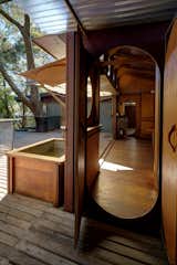 Doors, Exterior, Swing Door Type, and Wood Nautical design inspires the construction of the kitchen, where doorways are elliptical with simple brass handles.  Photos from This Home For Sale in the Australian Bush Has Magical Tree House Vibes