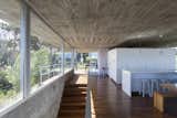 Dining Room, Bar, Table, Stools, Pendant Lighting, Bench, and Medium Hardwood Floor On one end of the top floor communal space, is a white volume, which neatly contains the kitchen, pantry, and toilet.  Photo 5 of 12 in A Concrete Abode in Uruguay Embraces its Beachfront Setting