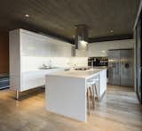 Kitchen, Wall Oven, Range Hood, Recessed, Ice Maker, Refrigerator, Cooktops, White, and Drop In An all-white kitchen works well with the concrete to give the space a cool, minimalist look.

  Kitchen Cooktops Ice Maker Drop In Photos from This Chilean Concrete Home Levitates Off a Coastal Slope