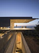Outdoor, Side Yard, Large Patio, Porch, Deck, and Concrete Patio, Porch, Deck The entrance passageway that leads to both the family room and bedrooms.

  Photo 5 of 14 in This Chilean Concrete Home Levitates Off a Coastal Slope