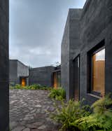 About 100 miles southwest of Mexico City, nine black concrete blocks in a forest clearing make up one family's holiday home. Designed by Mexican architect Fernanda Canales with landscaping by Claudia Rodríguez, Casa Bruma makes elegant use of a construction material that's commonplace in Latin America. The texture of the black board-formed concrete contrasts with the simple, rectilinear forms of the individual parts of the residence that surround a central patio paved with stone.