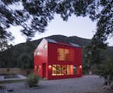Exterior, House Building Type, Prefab Building Type, Small Home Building Type, Metal Roof Material, Metal Siding Material, and Saltbox RoofLine The distance between homes in the area allowed architect Felipe Assadi to make a grand gesture by painting the two-level house bright red to complement the intense green of the surrounding trees, and to "activate the relationship between the landscape and the project through contrast."  Photos from This Modular Home in Chile Has Us Seeing Red—in a Good Way