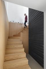 Staircase and Wood Tread The walls of the living area are covered in horizontal black slatted wood, which gives the interiors of modern, Scandinavian feel.  Photo 12 of 12 in A Family Retreat in Quebec Gets a Striking White Addition