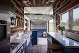 The kitchen walls are lined with reclaimed barnwood. LED accent strips were installed behind wine racks to add a rustic-yet-sophisticated element to the design. Automation is woven into the design with linear actuator TV lifts, and touch-activated storage door openers.  Photo 6 of 20 in This Oregon Company Crafts Exceptional Tiny Homes Starting at $40K