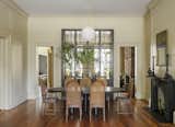 Dining Room, Chair, Table, Medium Hardwood Floor, Standard Layout Fireplace, and Pendant Lighting The dining area is located in the drawing room on the first level.  Photo 5 of 21 in An Old Charleston Row House Is Elegantly Modernized With a Southern Twist