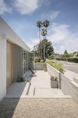 Outdoor, Front Yard, Small Patio, Porch, Deck, Raised Planters, Concrete Patio, Porch, Deck, and Horizontal Fences, Wall On the sides of the front folding glass doors are vertical cement board fins that emphasize the street-side corner. 

  Photos from A Cramped Midcentury Bungalow Gets a Luminous New Addition