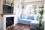 Living Room, Sofa, Standard Layout Fireplace, Dark Hardwood Floor, and Shelves In the living area is a large IKEA couch and sofa bed. There is also a built-in electric fireplace with a 40-inch Smart TV. 

  Photo 4 of 11 in Own This Stylish, Energy-Efficient Tiny Home For $69K