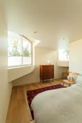 Bedroom, Medium Hardwood, Recessed, Chair, Dresser, Bed, Rug, and Table The bedrooms and gallery spaces are located within the concrete boxes.  Bedroom Chair Recessed Table Rug Photos from This Futuristic Japanese Building Is Not Your Everyday Tree House