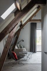 Bedroom, Concrete Floor, Floor Lighting, Chair, and Rug Floor Rough, scrubbed concrete and rounder plastering contrast with the restored timber roof beautifully.  

  Photos from An Old Belgian Fortress Breathes New Life as a Charming B&B