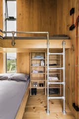 Bedroom, Bunks, Light Hardwood, Storage, and Shelves In the second building is a multi-purpose room with a fold-down bed, a kitchenette, and another sleeping area with a bathroom.  Bedroom Shelves Bunks Light Hardwood Photos from Three Timber Cabins Form a New Zealand Architect's Family Retreat