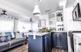 Kitchen, Drop In Sink, Microwave, Ceramic Tile Backsplashe, Pendant Lighting, Range, Colorful Cabinet, White Cabinet, and Medium Hardwood Floor Benjamin Moore Blue Note defines the peninsula cabinets.  Photo 4 of 11 in Budget Breakdown: A Tired RV Is Refreshed and Relisted For $21K