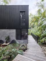 On one side of the home is a boardwalk that runs alongside verdant tropical plants. This boardwalk takes residence from the interior of the house, and goes out to the rainforest.