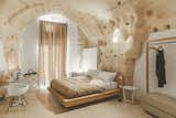 Bedroom, Floor Lighting, Night Stands, Table Lighting, Bed, Chair, and Terrazzo Floor The plaster was added to sections where the masonry was compromised.  Photo 11 of 16 in Stay in This Extraordinary Cave Hotel in Southern Italy