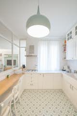 Kitchen, Marble Counter, Pendant Lighting, Cement Tile Floor, Range Hood, Vessel Sink, and Cooktops Within the kitchen is a discreet, built-in pantry that disappears when not in use.  Photo 5 of 12 in A Revamped Modern Home Is Sprinkled With Old-World Charm