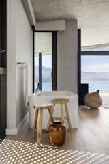 Bath Room, Light Hardwood Floor, Freestanding Tub, and Stone Slab Wall A bathroom that looks out to the lagoon.

  Photos from An Elegant South African Home Embraces Mesmerizing Views