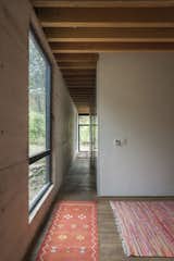 Hallway, Medium Hardwood Floor, and Rug Floor The ample amount of large windows draw much sunlight into the home.  Search “officefloors--medium-hardwood” from Upcycled Trees Cloak This Modern Mexican Home