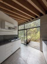 Kitchen, Cooktops, White, Concrete, Concrete, Concrete, and Range Hood The kitchen features a sleek, modern design.  Kitchen Concrete White Cooktops Concrete Photos from Upcycled Trees Cloak This Modern Mexican Home