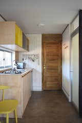 Kitchen, Drop In Sink, Ceiling Lighting, Cooktops, Wood Counter, Wood Cabinet, and Refrigerator The kitchen area and living/dining spaces are located on the first level, along with a bathroom.  Photo 4 of 11 in A Patagonian Prefab Cabin Is Built to Withstand Volatile Climates