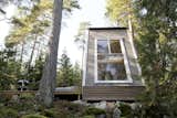 Nido Tiny Cabin by Robert Falck exterior three panel window with white siding in forest landscape
